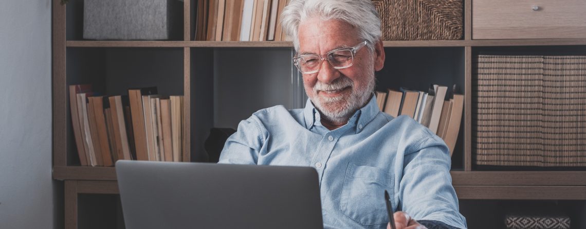 Older man working from home at laptop.
